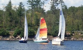 Three Mazinaw boats sail in close company with a backdrop of broken trees.  Photo by Lynda Dunal.